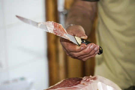 A person cutting ham shows a piece of ham with some bacon pieces.