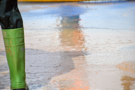 muddy ground, on the left side the boot of a worker, who is cleaning the groundの写真素材