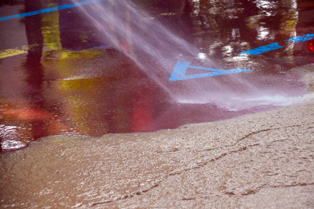 A worker uses a pressurized water hose to dislodge and remove mud from the ground after a street flood.の写真素材