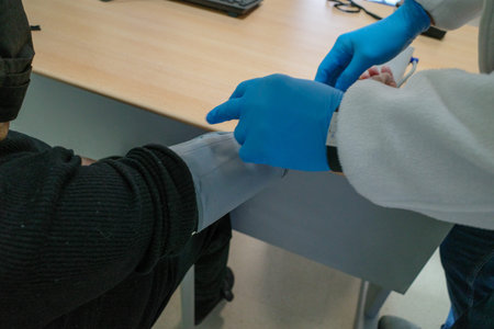 A nurse wearing blue gloves checks if the blood pressure monitor is correctly positioned before...