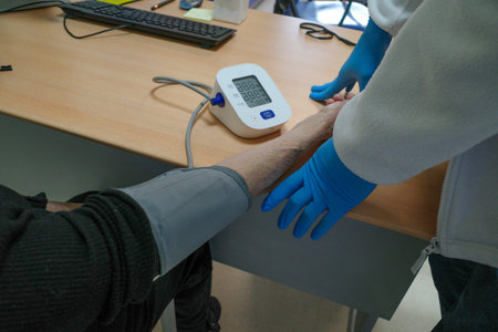 The doctor measures a patient's blood pressure with a sphygmomanometer.