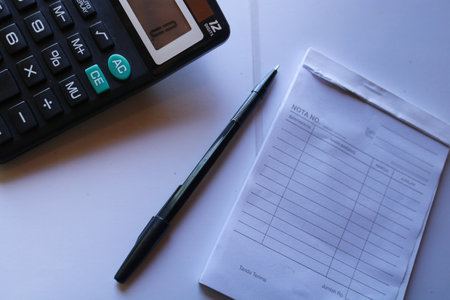 notepad calculator and pen on a white desk in the office, this photo was taken at the cashierの写真素材
