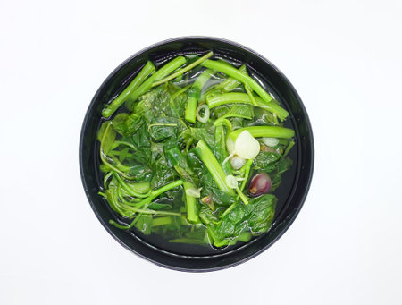 Vegetable spinach with shallots placed in a black bowl against a white backgroundの写真素材