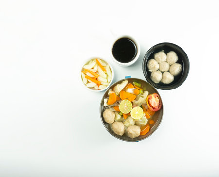Meatball soup on a wooden cutting board with napkins on a white background.