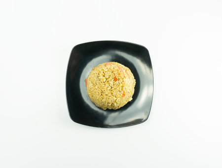 Fried rice served with fresh tomatoes and meatballs in a black tosca plate and pickles on a white bowl on a white backgroundの写真素材