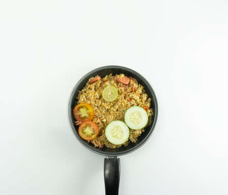 Fried rice served with fresh tomatoes and meatballs in a teflon bowl black tosca and pickles on a white bowl on a white backgroundの写真素材