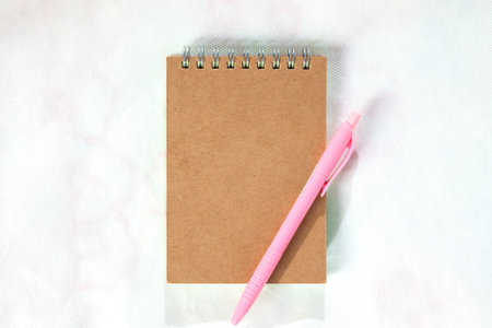 Brown front cover notebook with pink pen isolated on Mattress White background