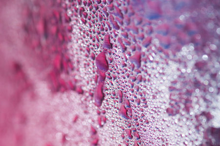 Water droplets on the glass with a colored background. Drops of water