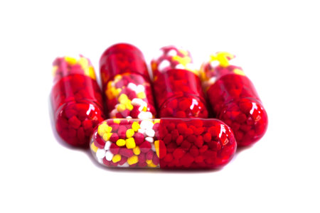 Medical red capsule with granules on white background