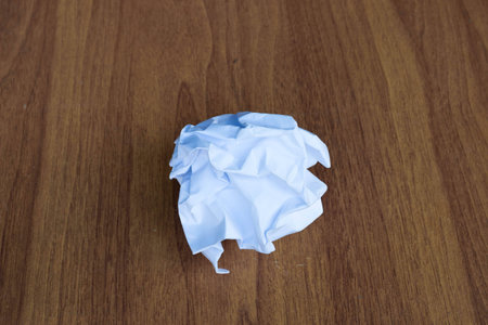 Ball of smashed sheet of paper over wooden table