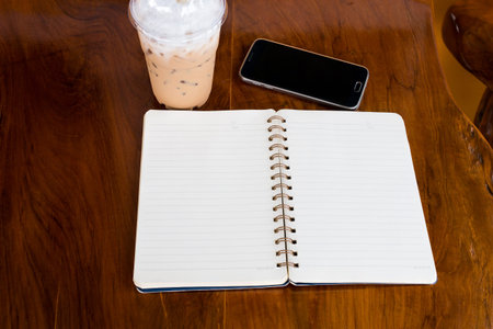 Open note book with coffee cup and smartphone on  wood tableの写真素材
