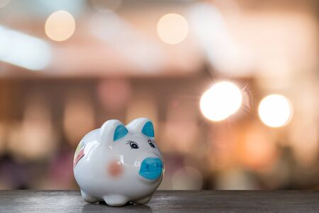saving money in piggy bank on wooden background over bokeh light in night,saving money for travel in holiday,christmas,new yearの写真素材