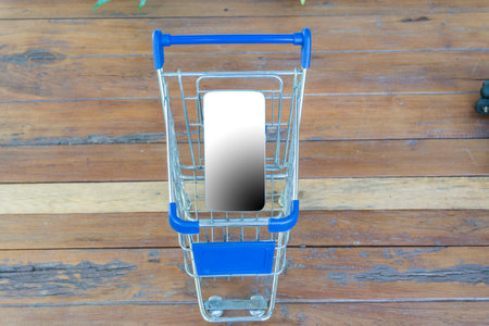shopping cart with smartphone on wood tableの写真素材