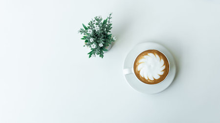 White cup of hot Latte art coffee with Flower Pot on white table