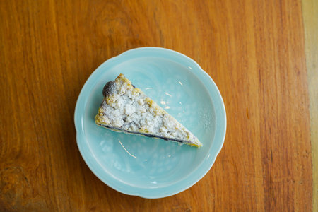 A piece of blueberry cake on a plate on the wood table