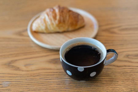 Fresh croissant with a cup of coffee on wood table