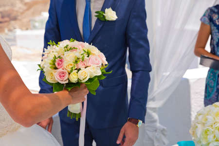 The bride and groom with a bouquet of flowers in his hands. Santorini, Greece.の写真素材