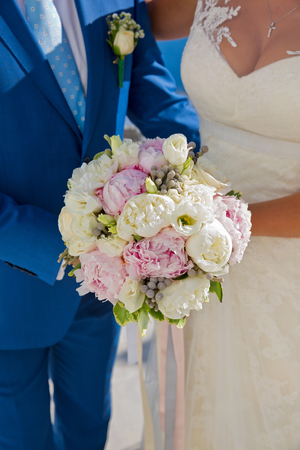 The bride and groom with a bouquet of flowers in his hands. Santorini, Greece.の写真素材