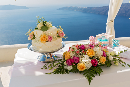 Wedding cake and bouquets of flowers on the table, against the sea. Greece.の写真素材