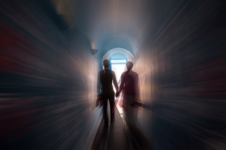 Young wedding couple goes through a dark archway to the lightの写真素材