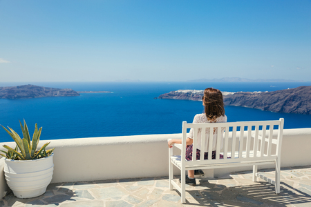 Young woman sitting on the bench and looking at seaの写真素材