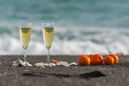 Two glasses of wine and tangerines on the sea sandの写真素材