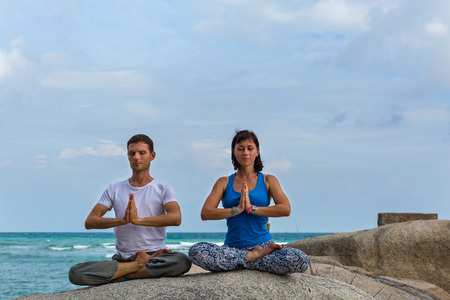 Young couple doing yoga on the beach in Thailandの写真素材
