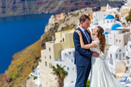 Wedding couple with bouquet of flowers on the background architecture of Santoriniの写真素材