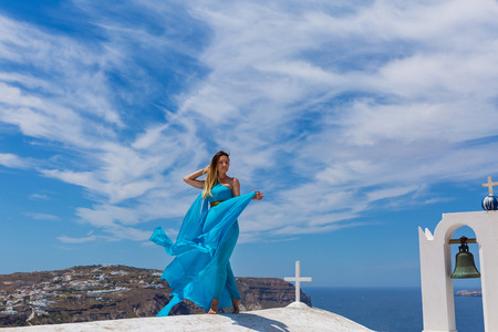 Young woman in blue dress on the roof next to the bell towerの写真素材