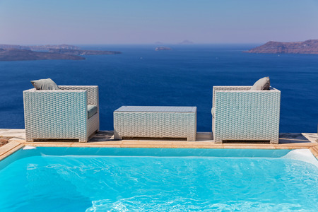 Table and comfortable chairs near the pool with sea viewsの写真素材