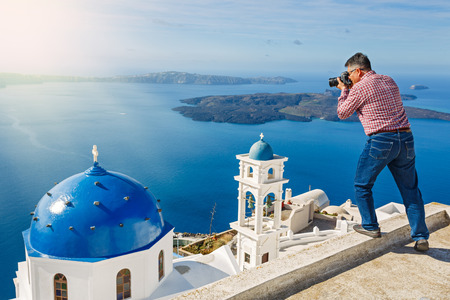 Man photographs the landscape of the volcanic island of Santorini, Greeceの写真素材