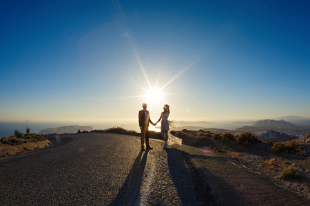 Silhouette of the bride and groom on the road against the seaの写真素材