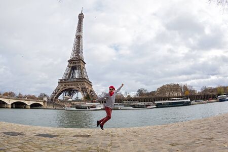 Man joyfully jumps high against the background of the Eiffel tower in Parisの写真素材