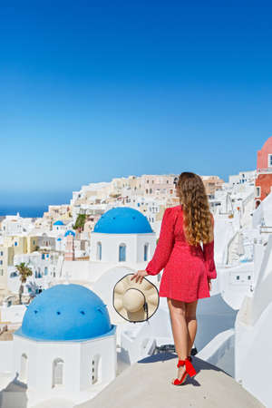 Beautiful, young woman on the roof of the Santorini island building looks at the landscapeの写真素材