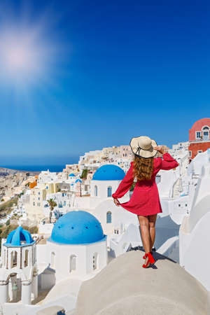 Beautiful, young woman on the roof of the Santorini island building looks at the landscapeの写真素材