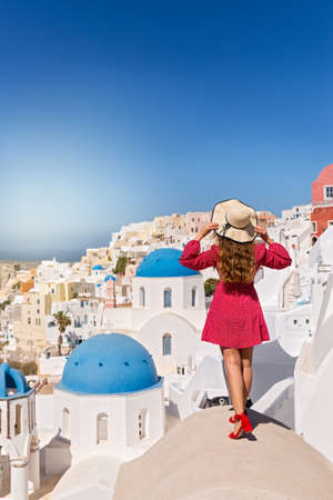 Beautiful, young woman on the roof of the Santorini island building looks at the landscapeの写真素材