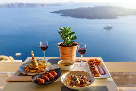 Dinner for two in a restaurant overlooking the sea and the island of Santorini, Greeceの写真素材