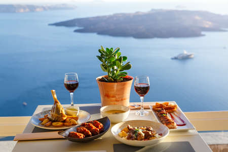 Dinner for two in a restaurant overlooking the sea and the island of Santorini, Greeceの写真素材