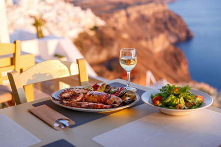 Dinner with seafood and wine on the background of the sea and sunsetの写真素材
