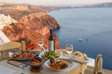Dinner for two in a restaurant overlooking the sea and the island of Santorini, Greeceの写真素材