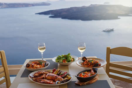 Dinner for two in a restaurant overlooking the sea and the island of Santorini, Greeceの写真素材
