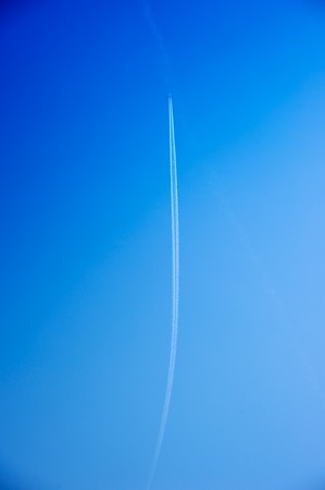 Airplane at high altitude with white condensation trailsの写真素材
