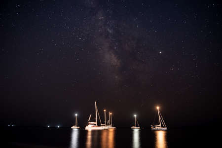 Night sky with the Milky Way Galaxy above some boats in Vlychada beach, Santoriniの写真素材