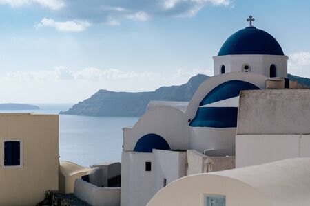 White church with blue dome in Oia village, Santorini island, Greece.の写真素材