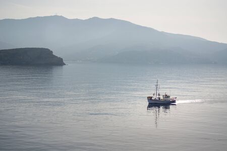 A fishing boat in the sea, early morning. Ios island, Cyclades, Greeceの写真素材