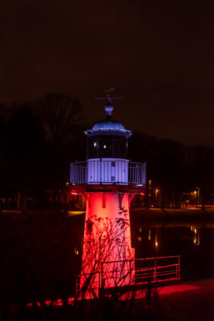 Red lighthouse at night at the side of a river.の写真素材