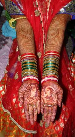 Indian bride's hands with henna tattoos and bracelets on her hands