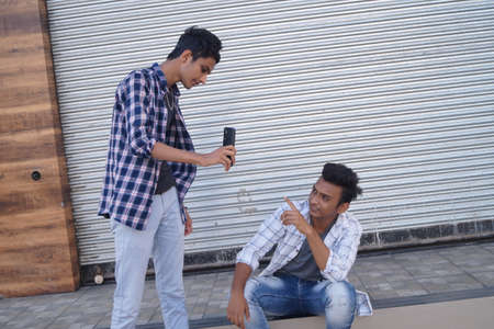 Young men friends using mobile phoneの写真素材