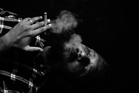 Addicted man exhaling smoke over black background