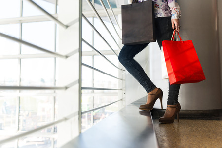 Female legs in jeans and gift bags and feet with tattooの写真素材